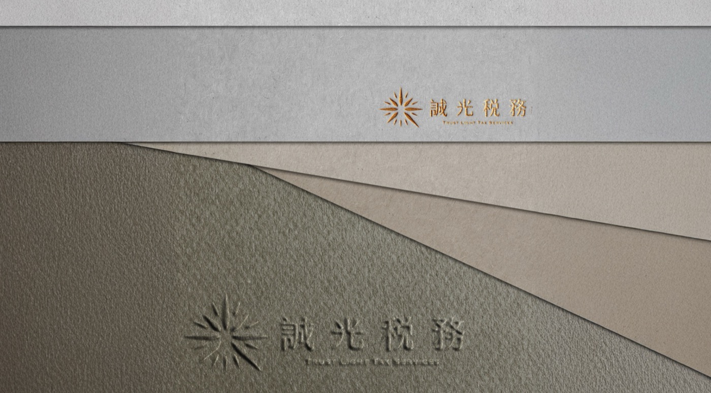 放射狀細線組成的標誌，一組燙金印在淺色紙上，一組壓凹在灰綠紙上