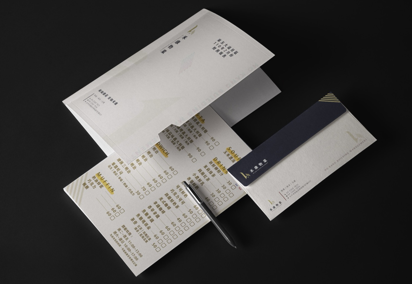 物業公司的長型信封、信紙與表單攤放在深色桌面上，三件用同一套標誌與色帶