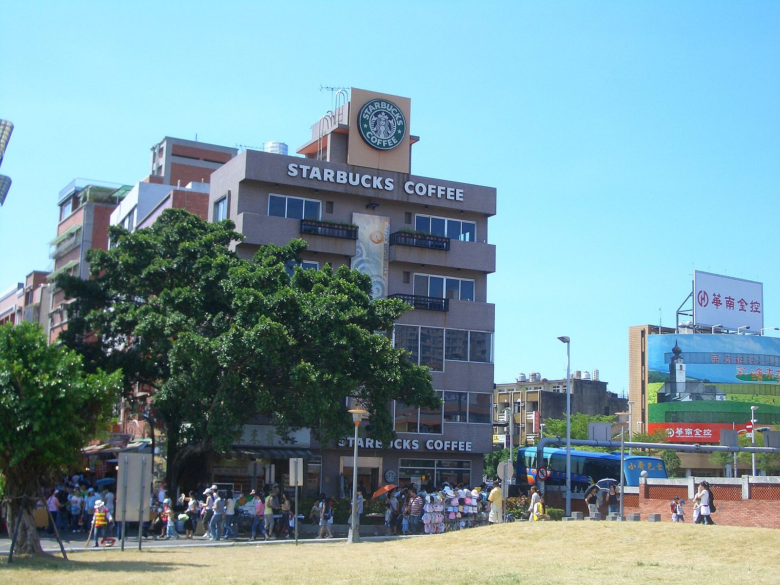 2006 年淡水捷運站旁的星巴克，樓頂是外圈寫著 STARBUCKS COFFEE 的綠色圓形標誌，樓面也掛著店名