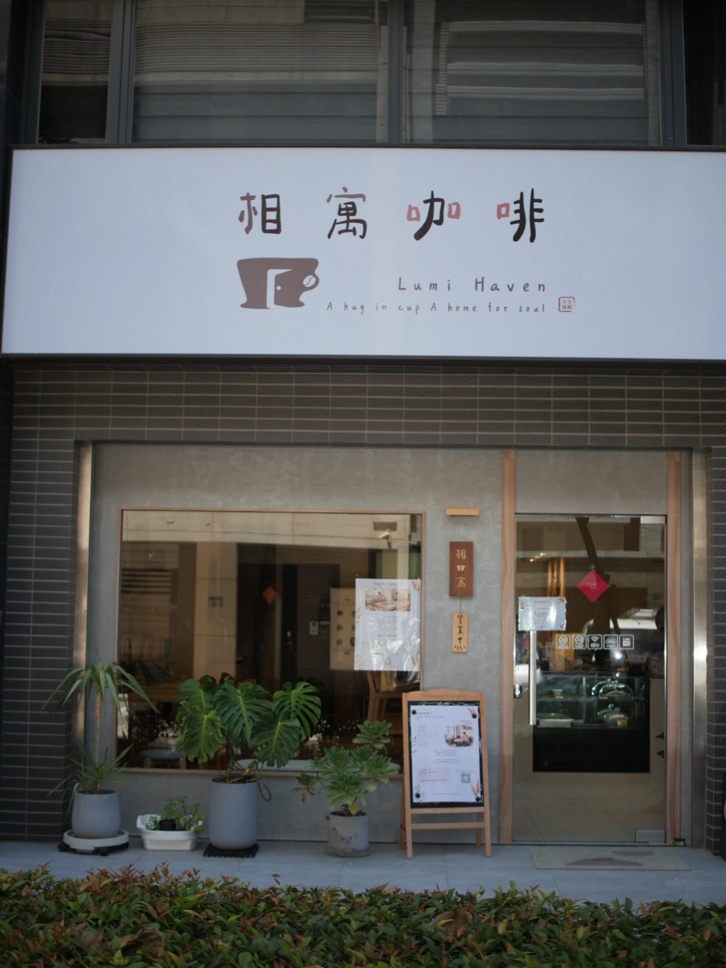 相寓咖啡的店門口,門邊立著一塊木框 A 字架立牌,旁邊牆上掛著直式木質門牌