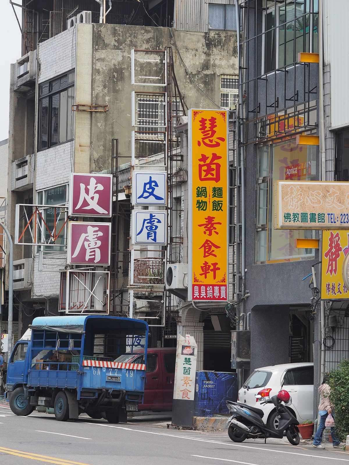 台南街邊的老建築，相鄰的兩塊直式招牌都寫著皮膚兩個大字，旁邊是一塊黃底紅字的素食店招牌