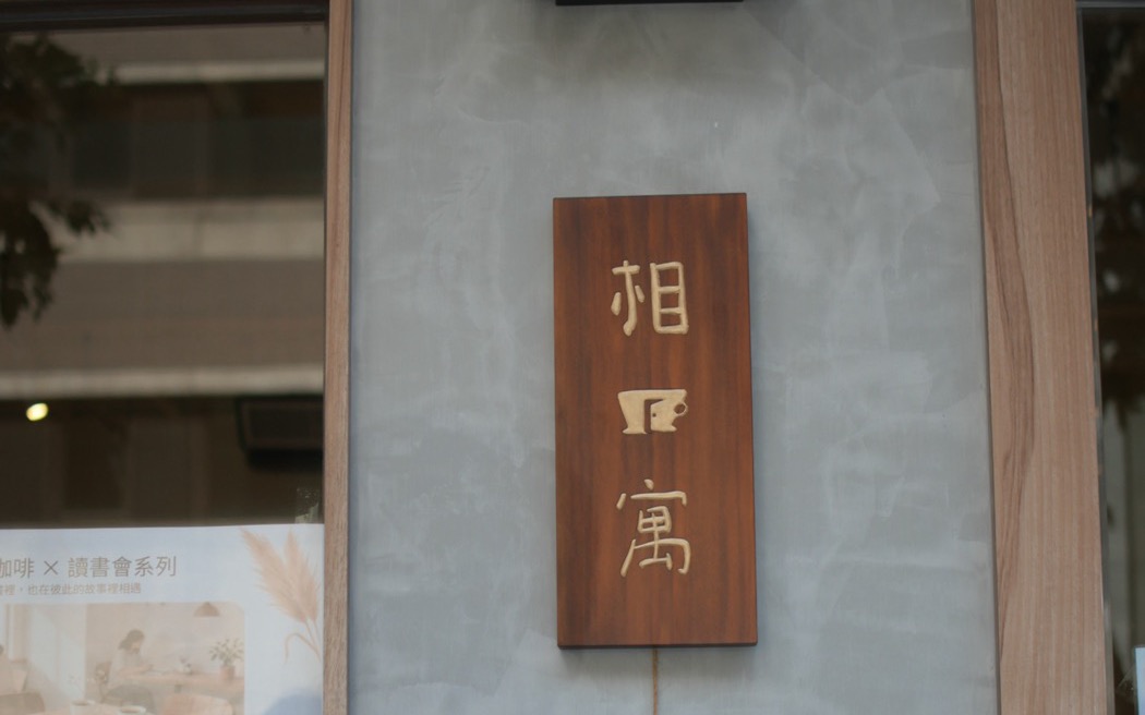 相寓咖啡門邊的木質直式門牌，店名的筆畫做在木板上，看得到每一筆的厚度