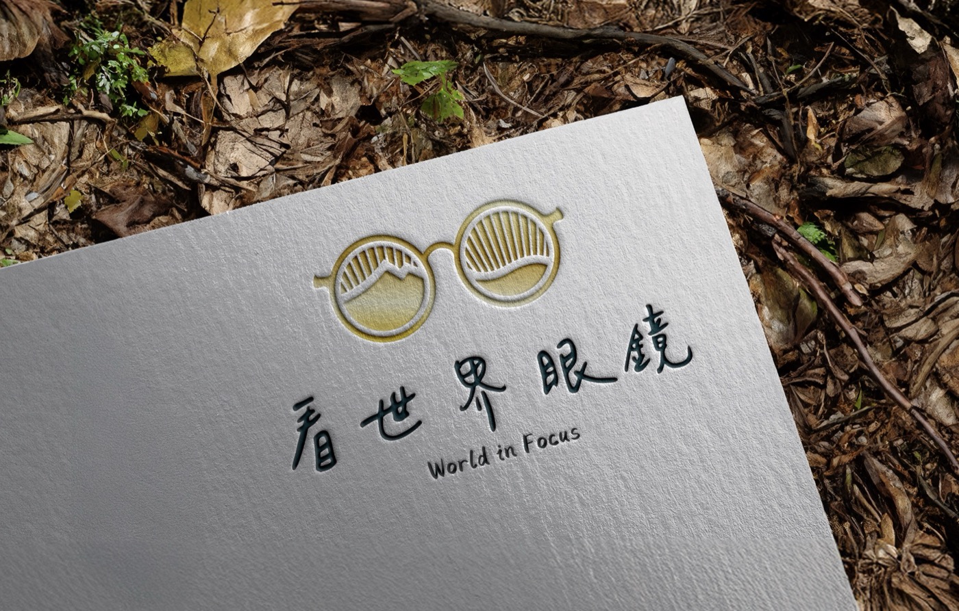 看世界眼鏡的標誌印在手工紙上，上方是兩個鏡片組成的眼鏡圖形，下方是手寫感的中文品牌名與英文標準字