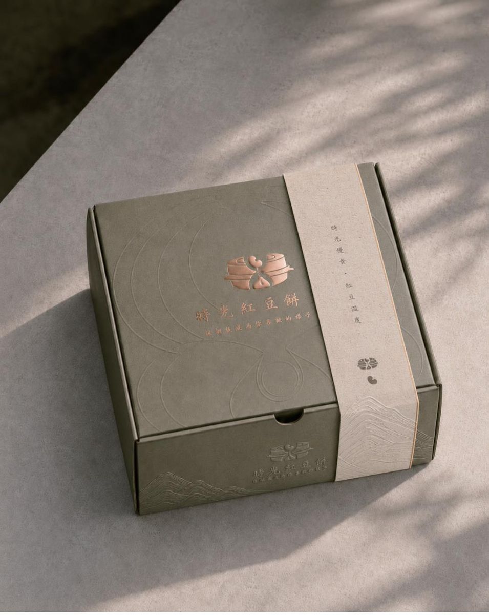 灰綠色禮盒上燙玫瑰金時光紅豆餅 logo,套著米色腰封