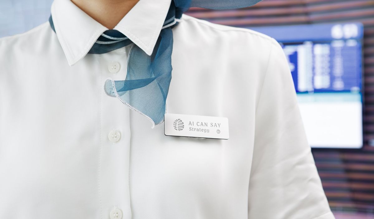 白襯衫胸前別著 AI CAN SAY 名牌