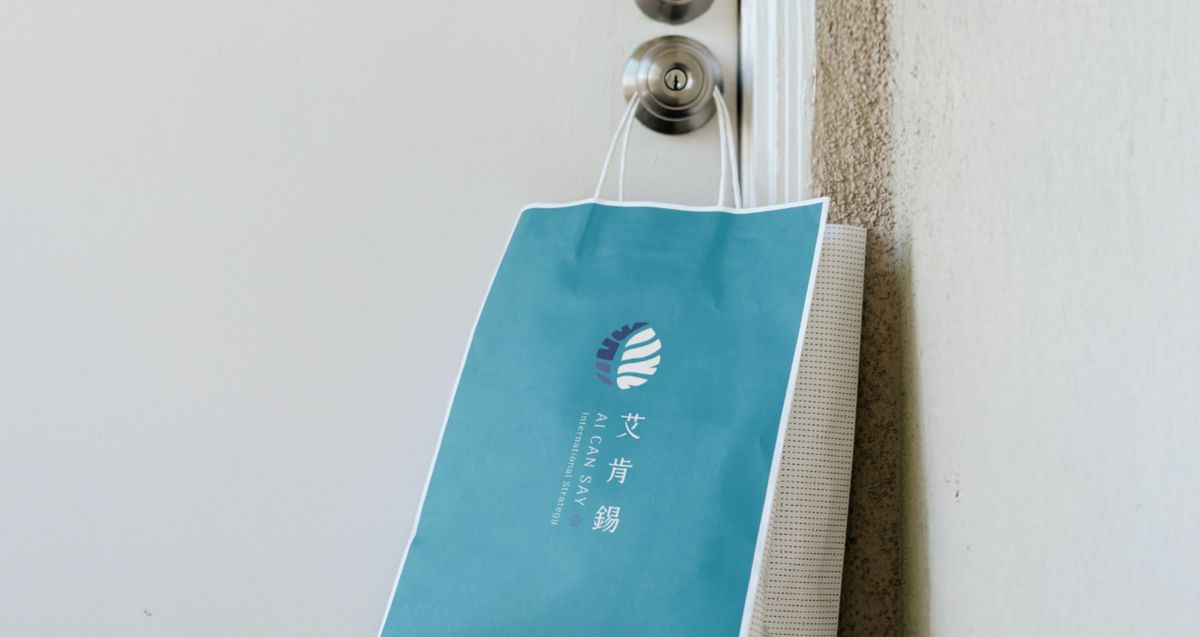 掛在門把上的智慧之藍提袋，印著艾肯錫直式 Logo
