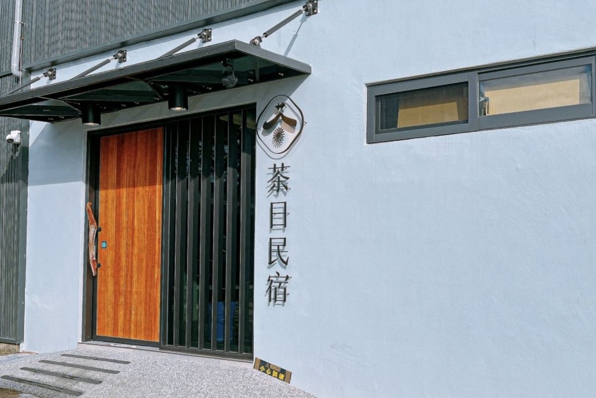 茶日民宿大門旁的白牆上，掛著茶字 Logo 與直式茶日民宿立體字