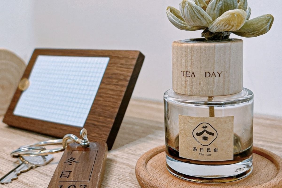 木牌房卡旁的 TEA DAY 擴香瓶，瓶身貼著茶日民宿標籤