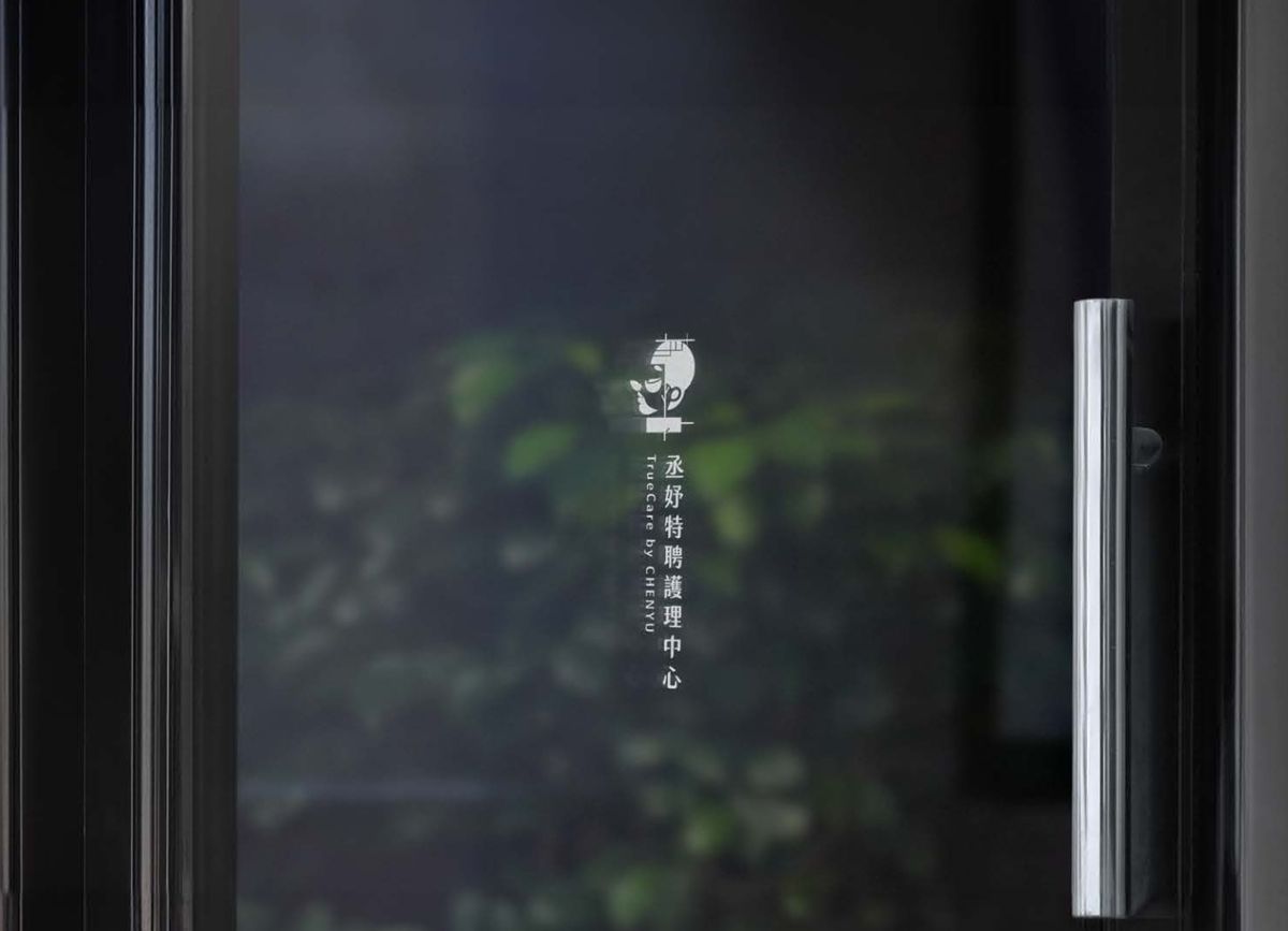 深色玻璃門上直式排列的白色丞妤標誌與字標