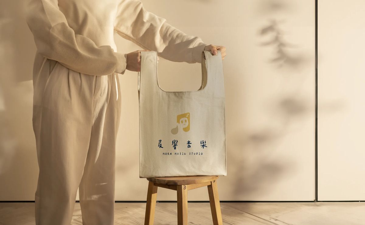 米白色帆布袋印著晨響音樂標誌，放在木頭凳子上