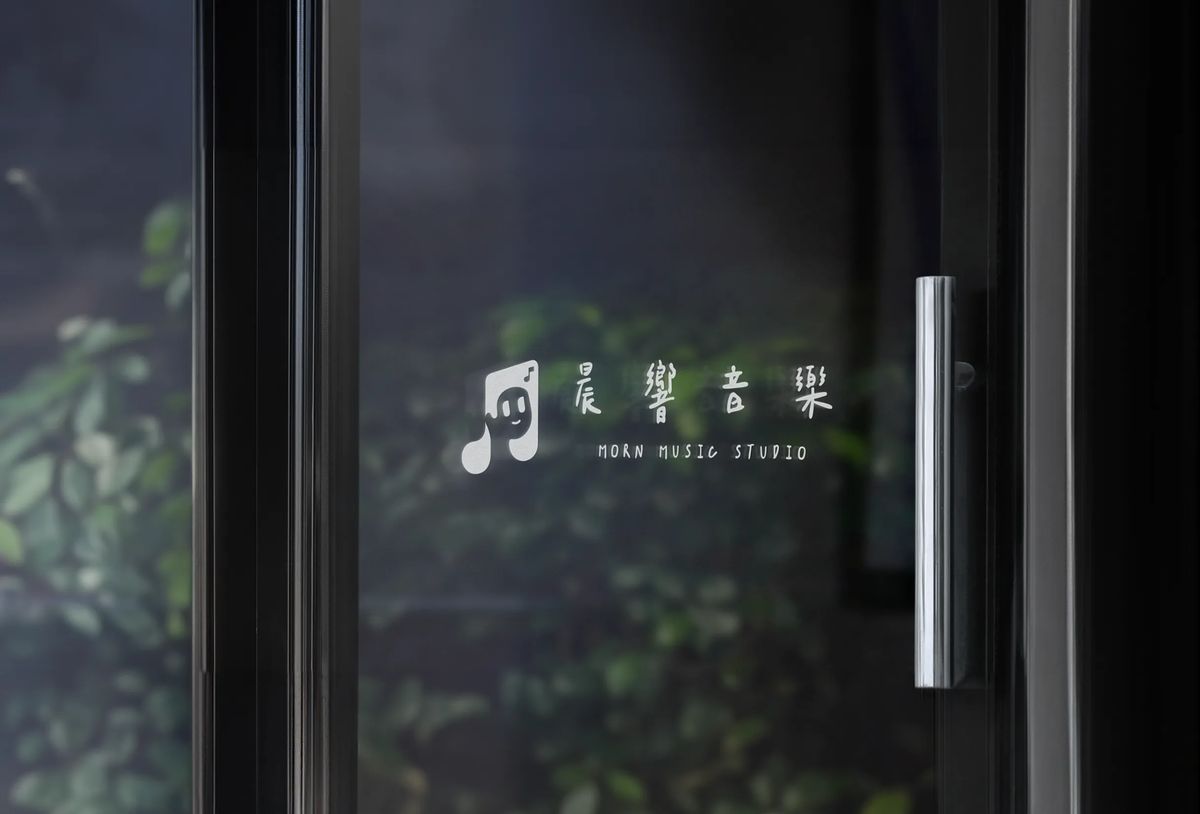 白色的晨響音樂標誌貼在深色玻璃門上，旁邊是金屬門把