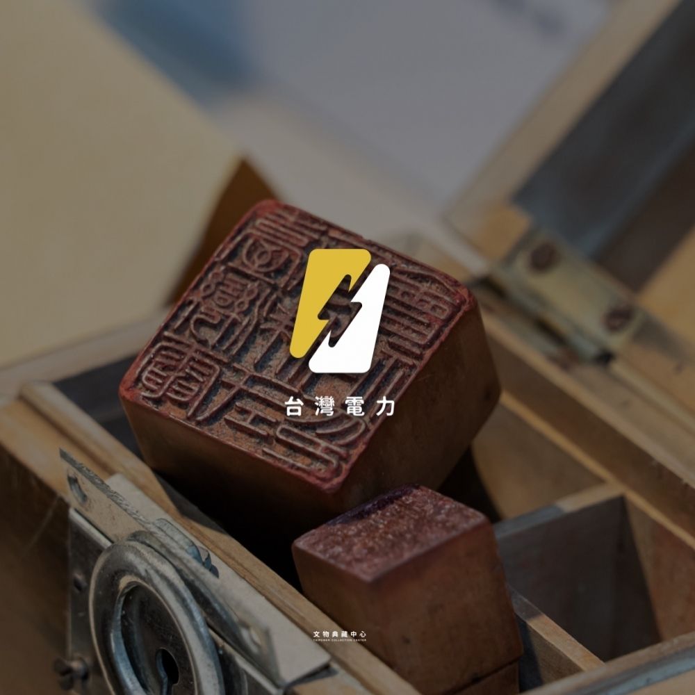 木盒裡的老印章，上面疊著黃白兩色電力符號與台灣電力字樣