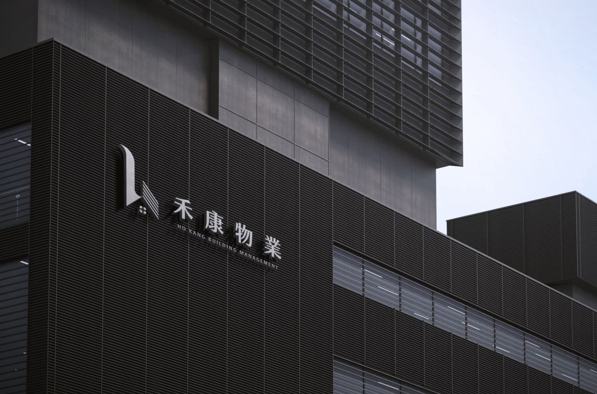 深色大樓外牆上的白色立體禾康物業 logo 與字標