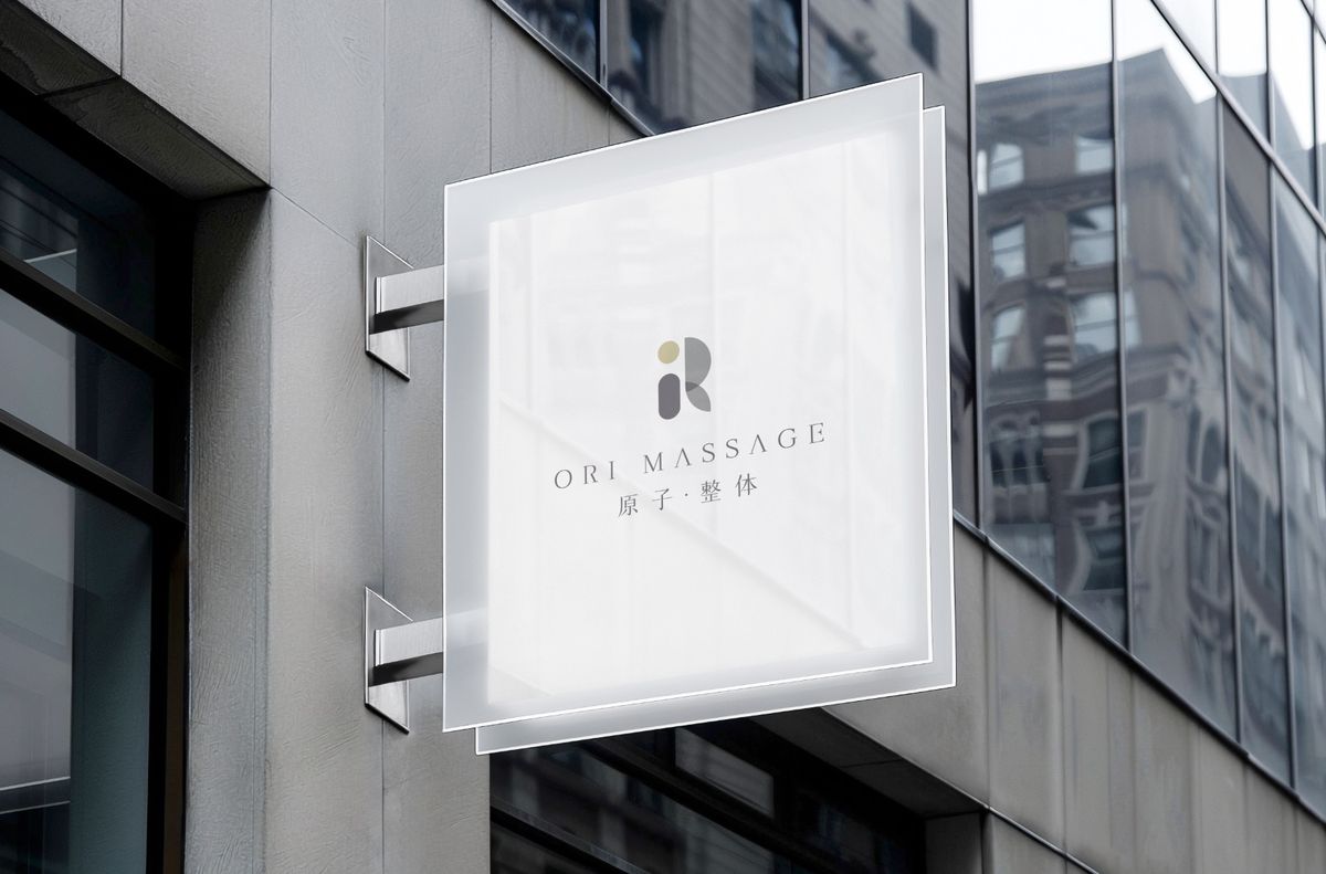 大樓外牆上的霧面白色側招，印著原子．整体 Logo 與 ORI MASSAGE